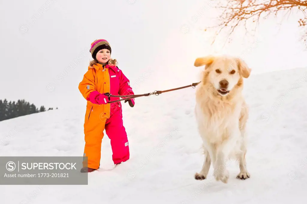 Girl walking dog in snow