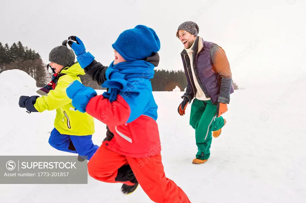 Man and two boys running in snow