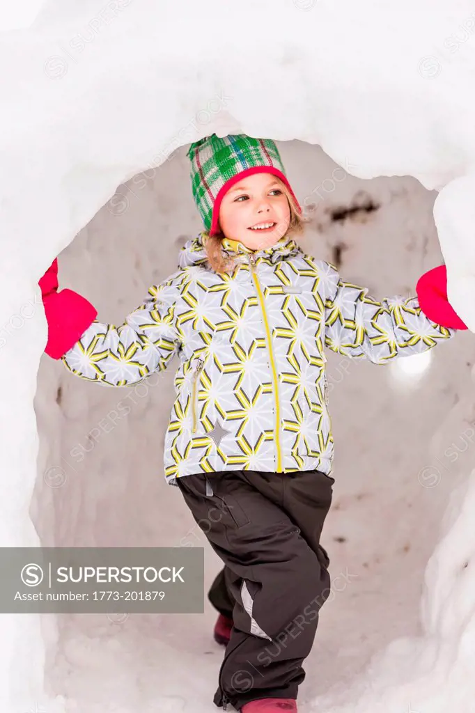 Girl wearing winter clothes standing in igloo