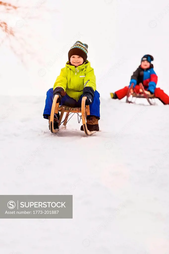 Two boys on toboggans in snow