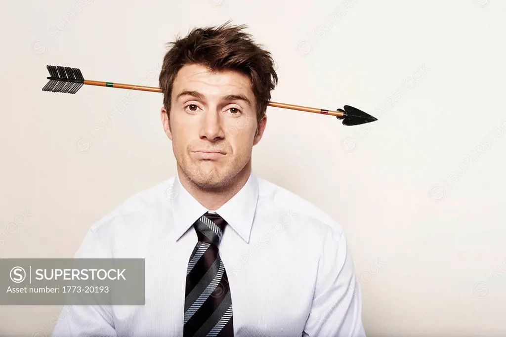 Business man with a large arrow through his head