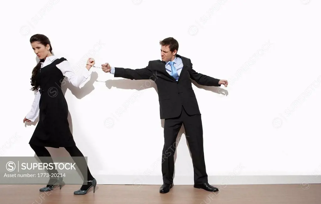 Woman and man handcuffed together pulling apart