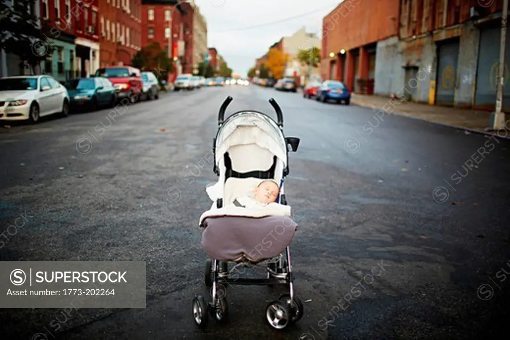 Baby boy asleep in push chair in middle of street