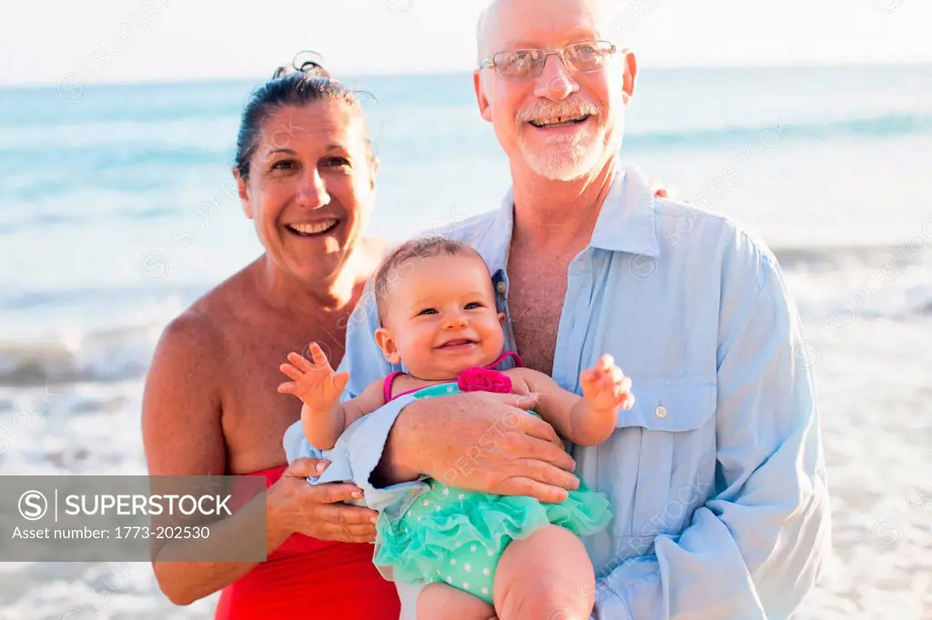 Grandparents holding granddaughter by sea, St Maarten, Netherlands
