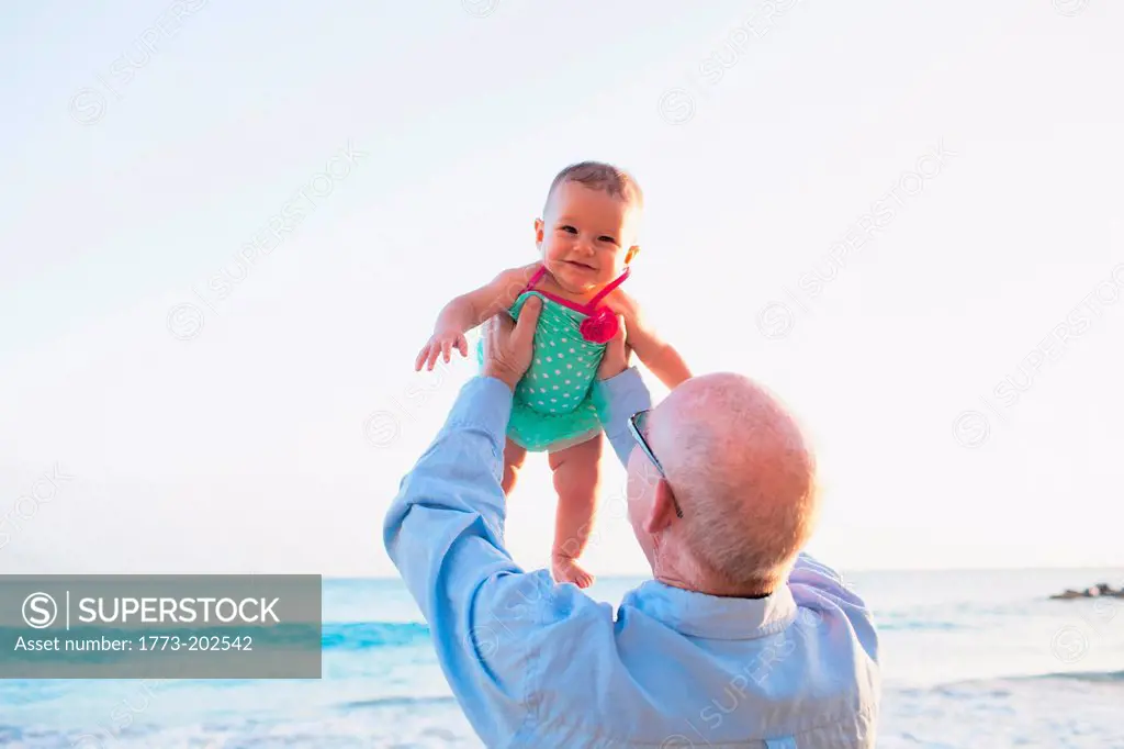 Grandfather lifting granddaughter above head, St Maarten, Netherlands