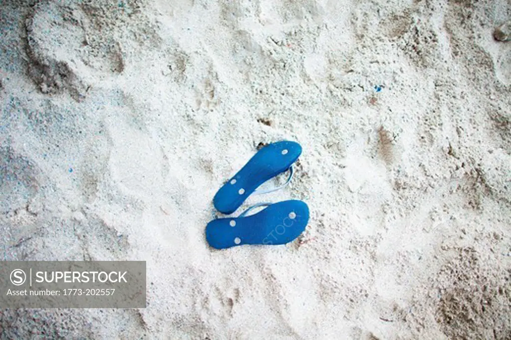 Pair of blue flip flops on sand