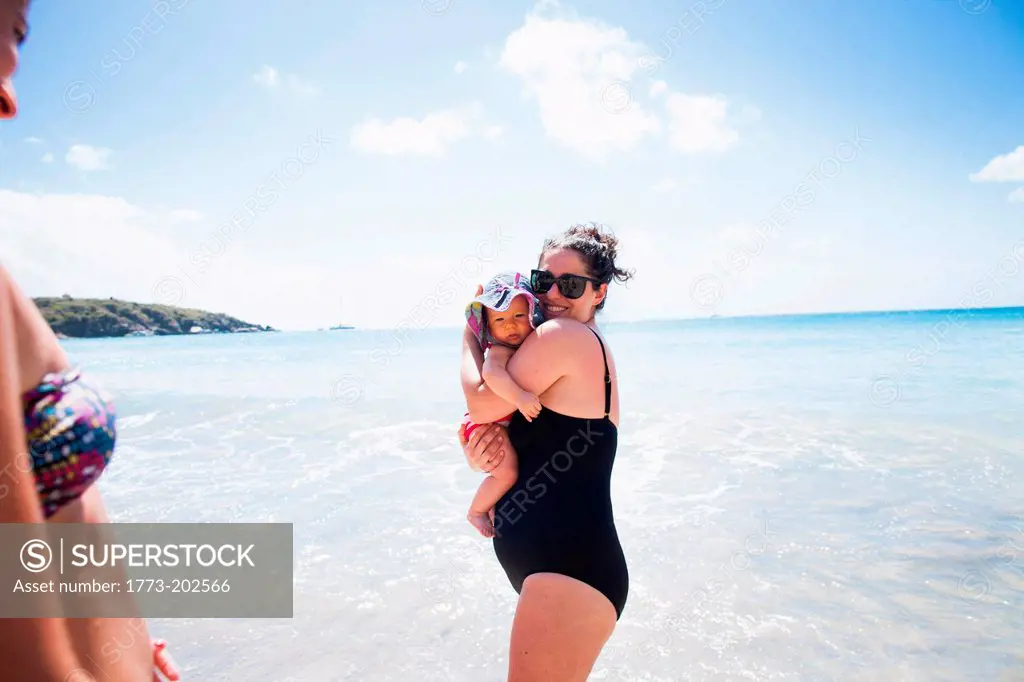 Mother holding baby daughter in sea, St Maarten, Netherlands