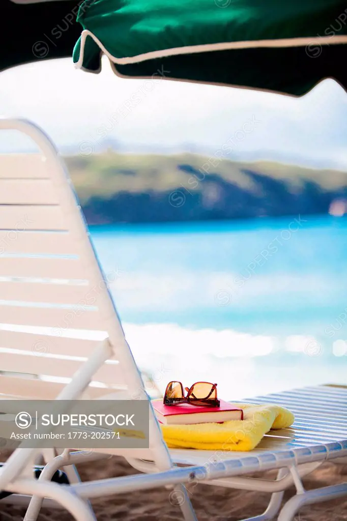 Sunglasses, towel and book on sun lounger