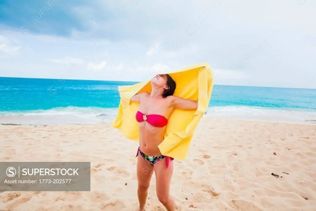 Woman holding yellow towel on beach, St Maarten, Netherlands