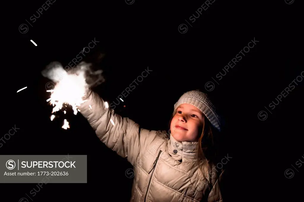 Girl holding sparkler at night