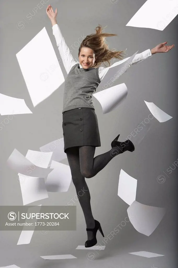 young business woman jumping with flying sheets of A4 white office paper