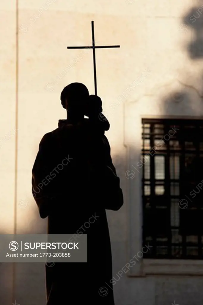 The silhouette of a religious statue outside of a church in the Alfama district of Lisbon, Portugal