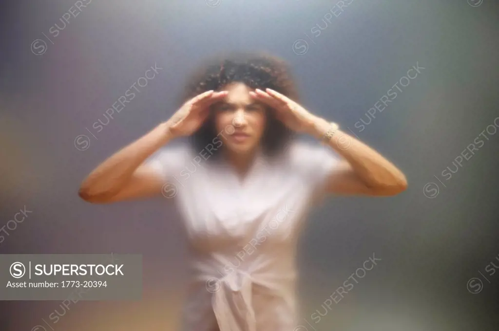 Blurred portrait of woman trying to see through frosted glass. Image shot through frosted office screen.