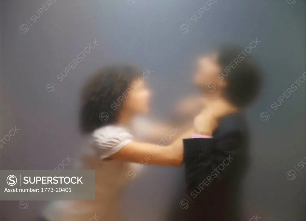 Blurred image of woman trying to strangle co_worker. Seen through frosted office screen.