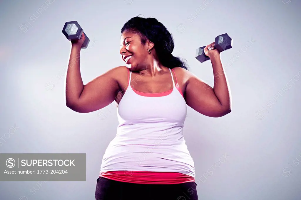 Mature woman using hand weights, smiling