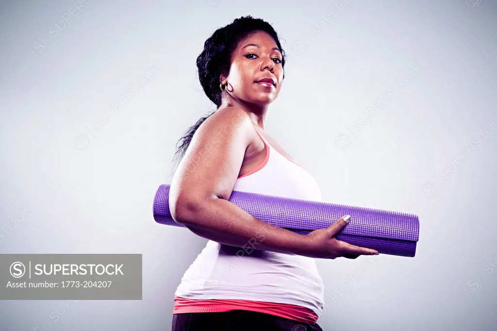 Mid adult woman holding yoga mat
