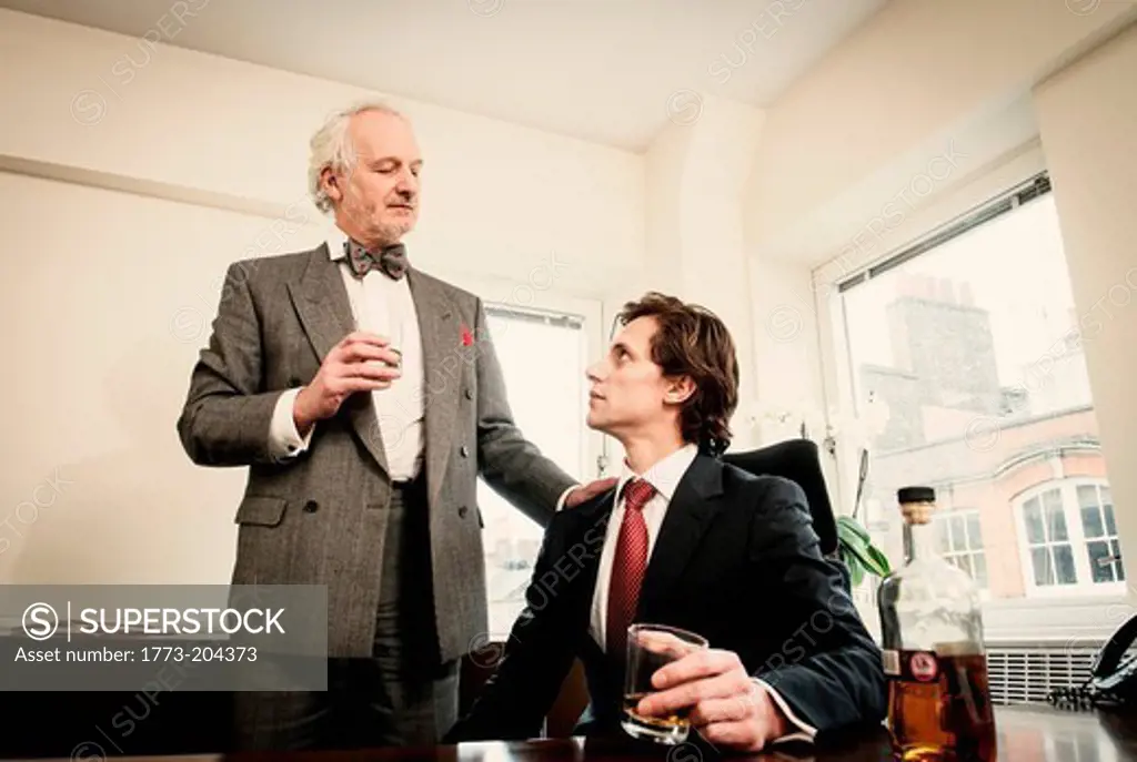 Two men drinking spirits in office