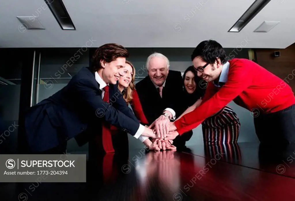 Business team putting their hands on top of each other at meeting table