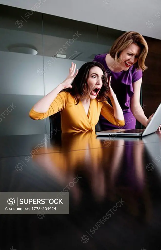 Two business executives reacting in shock at laptop