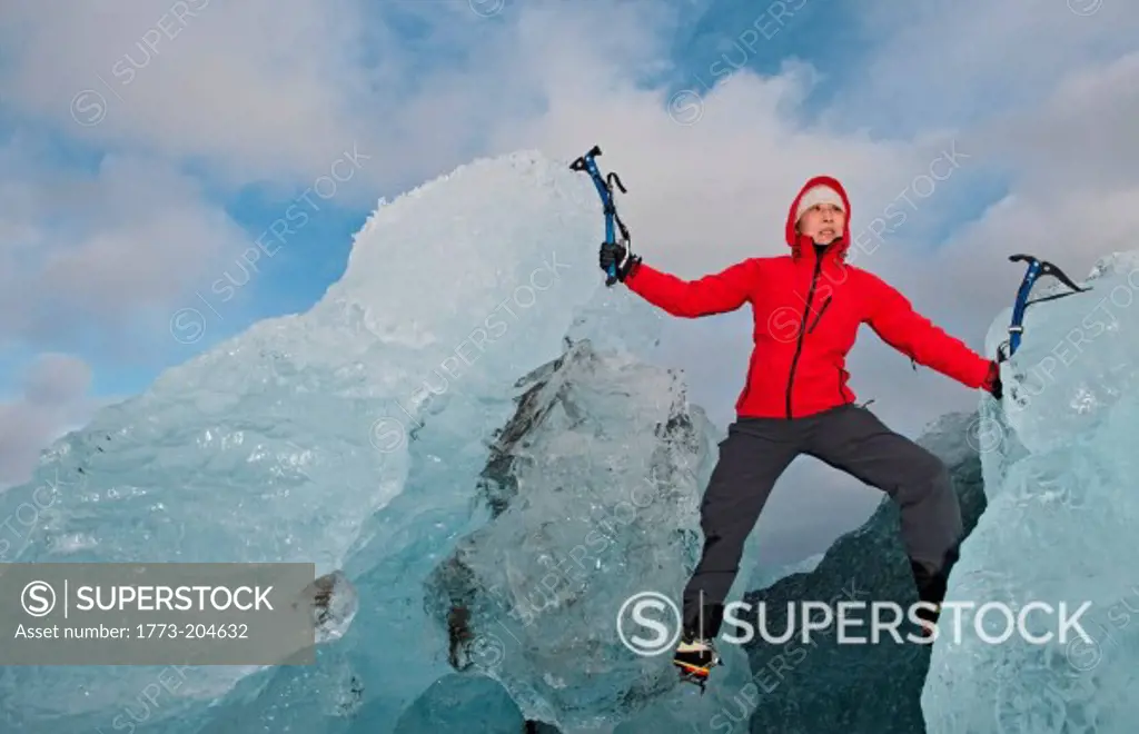 Mature woman climbing on iceberg, Jokulsa Loni, Iceland