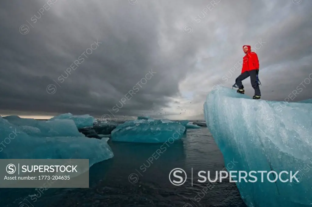 Mature woman climbing on iceberg, Jokulsa Loni, Iceland
