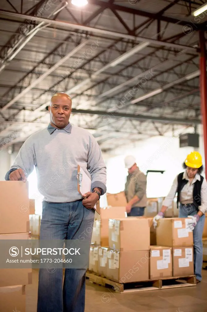 Portrait of male warehouse worker leaning on boxes