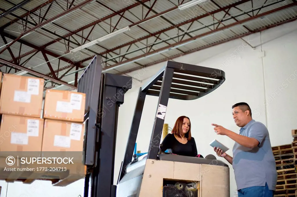 Warehouse workers and forklift truck with boxes