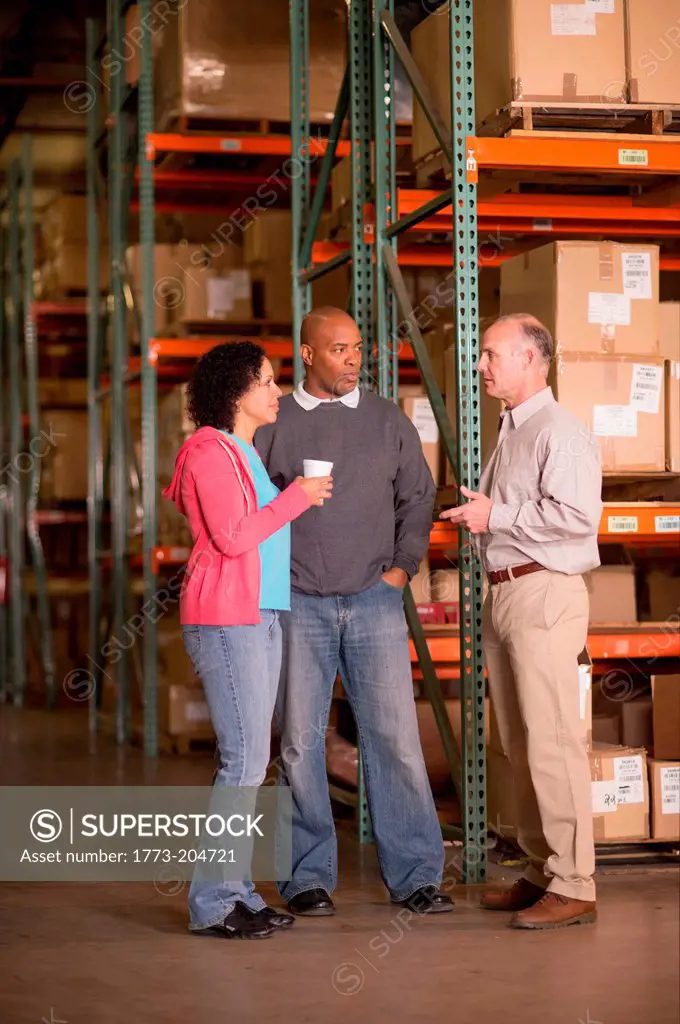 Warehouse workers standing by shelves with boxes