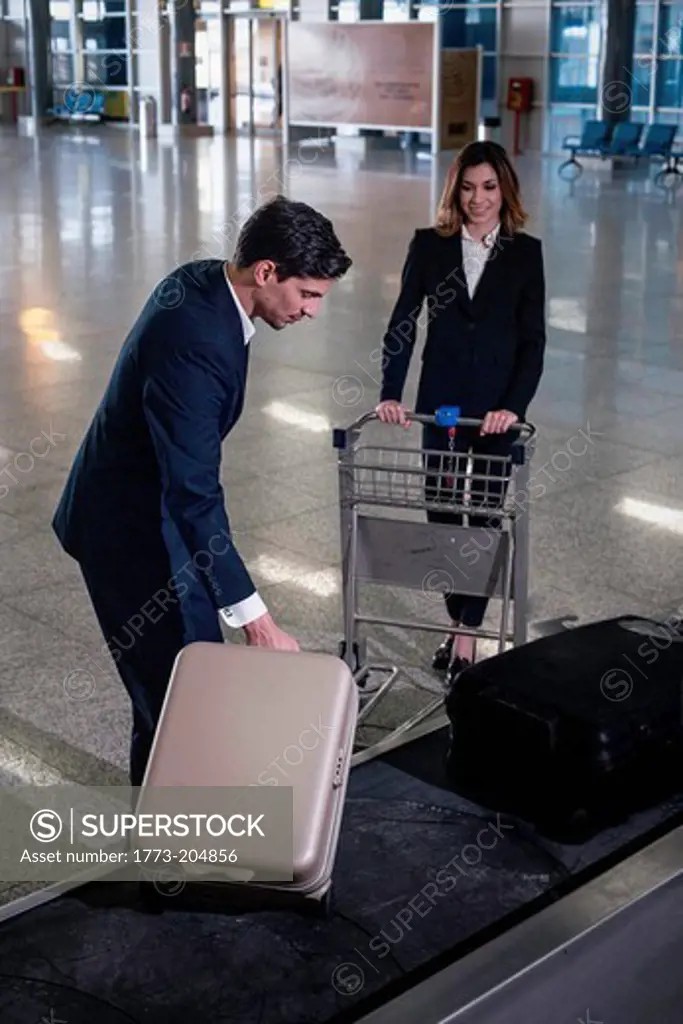 Businesspeople in airport at baggage reclaim