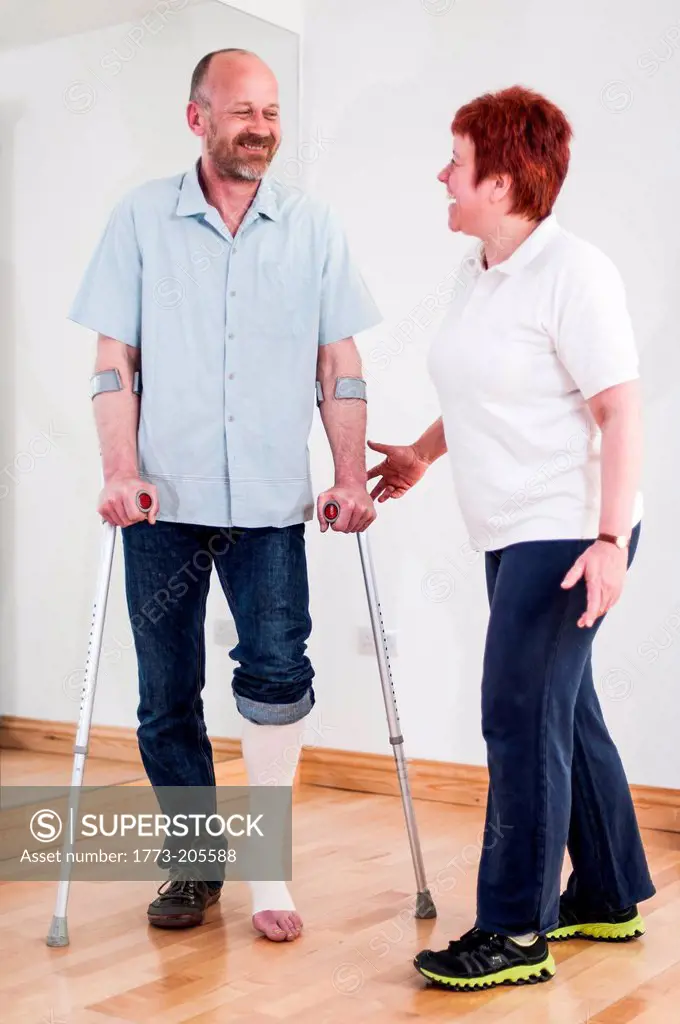 Man using crutches talking to woman