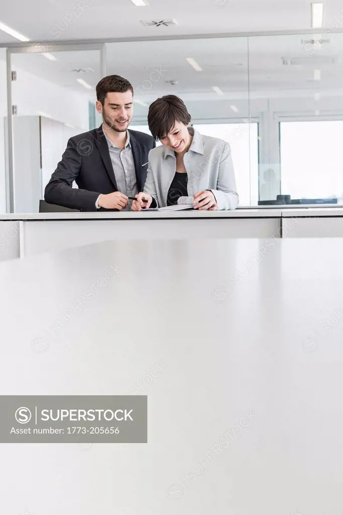 Businesspeople standing doing paperwork in office