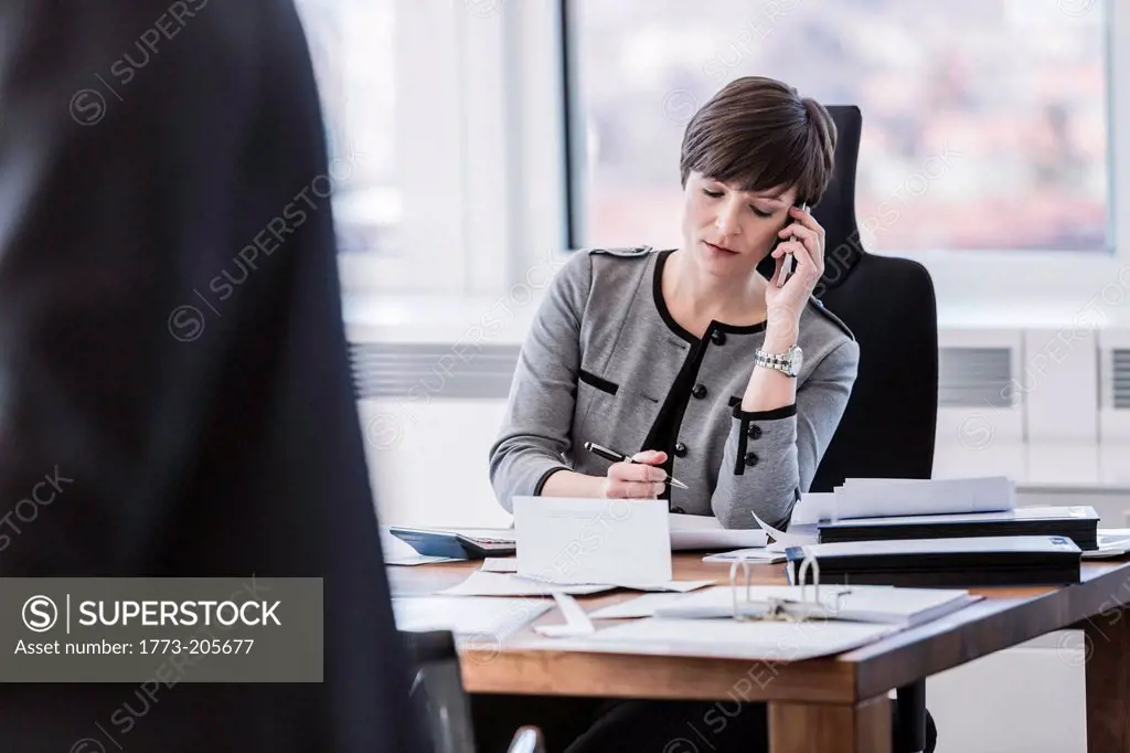 Businesswoman sitting at desk making telephone call