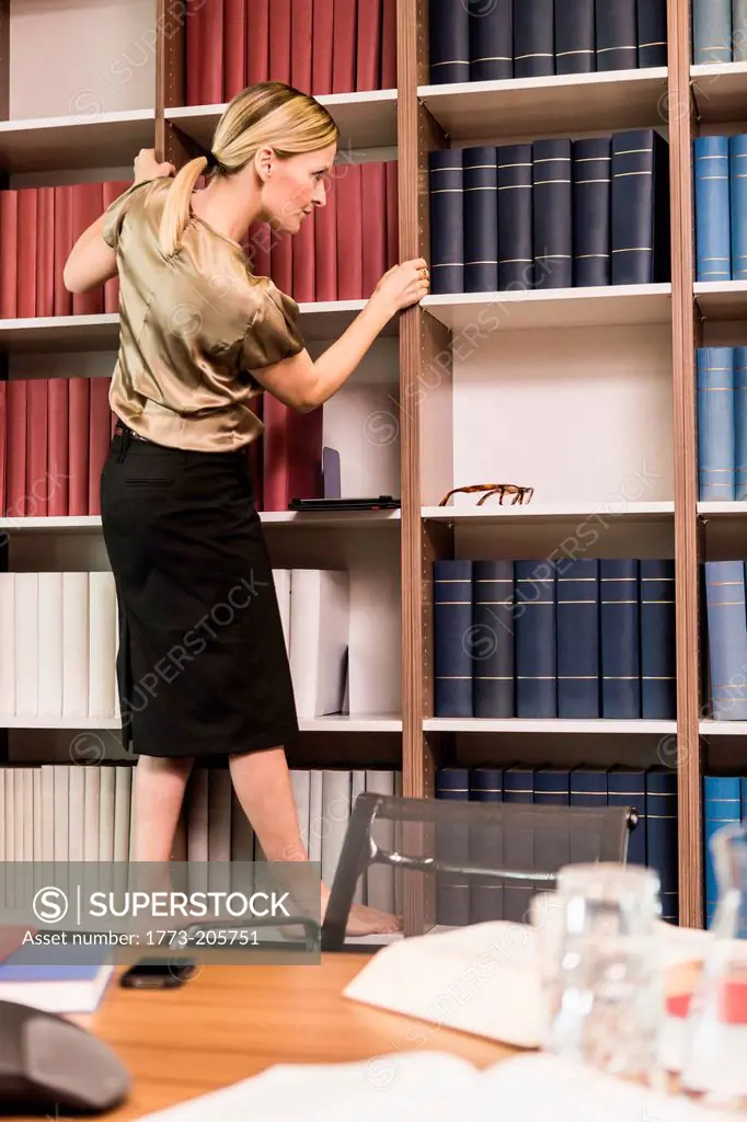 Female lawyer choosing books from bookcase