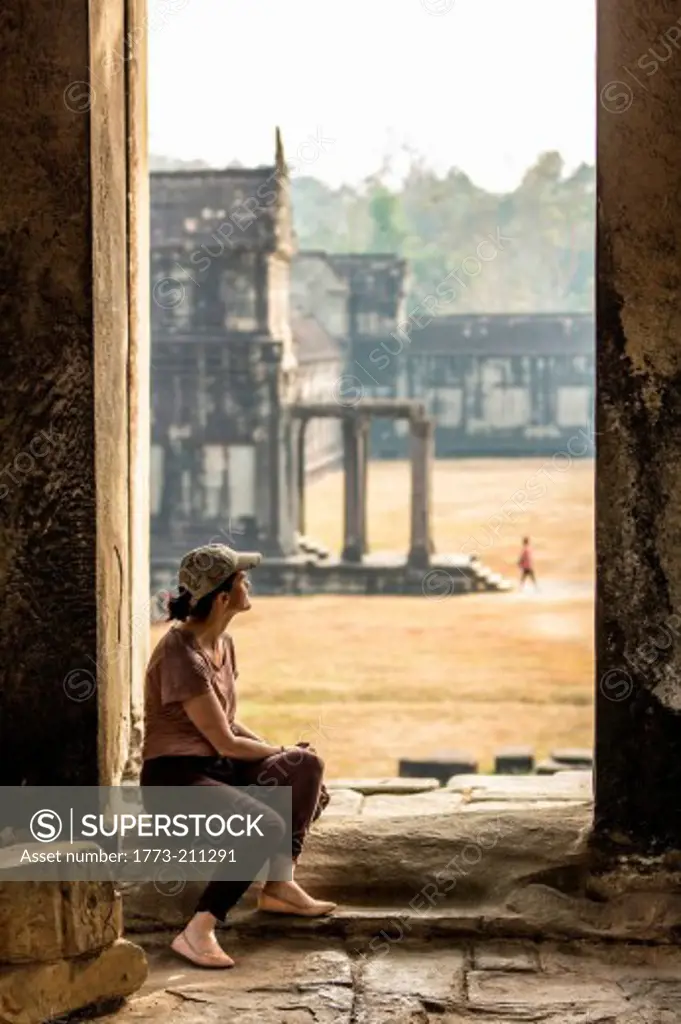 Tourist sitting in temple in Angkor Wat, Siem Reap, Cambodia