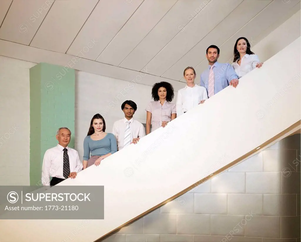 Seven office workers of different ages and sexes posing on staircase