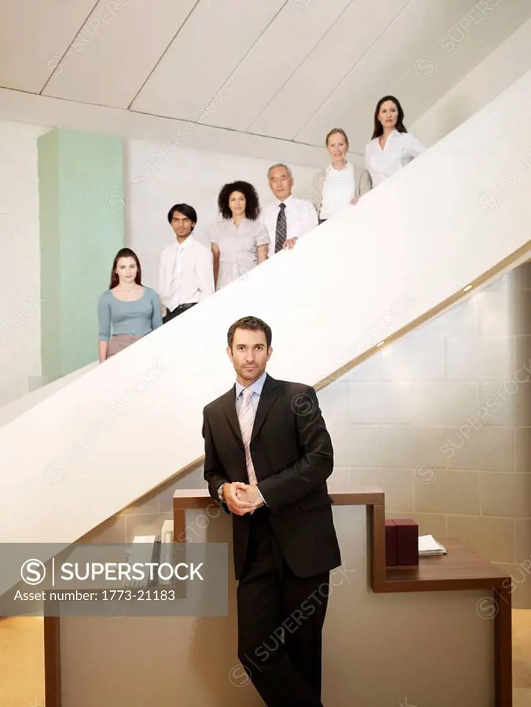 Six office workers of different ages and sexes posing on staircase, man in forground