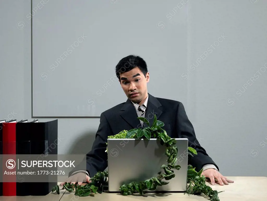 Man by desk beeing attacked by plants