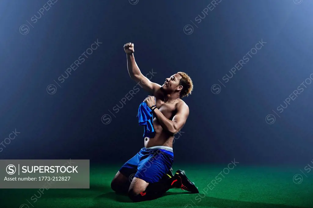Male soccer player kneeling with arm raised