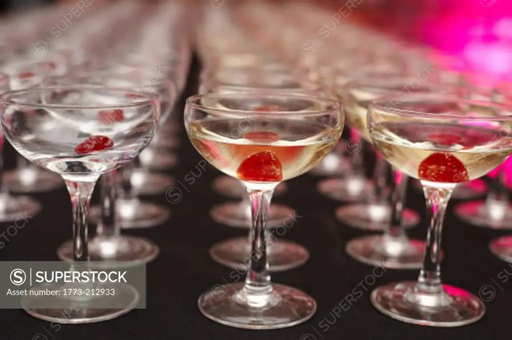 Rows of drinking glasses with maraschino cherry inside