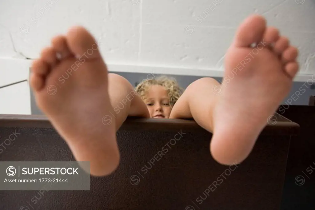 Playful portrait of little girl taken from underneath_ showing the bottom of her feet and her smiling face
