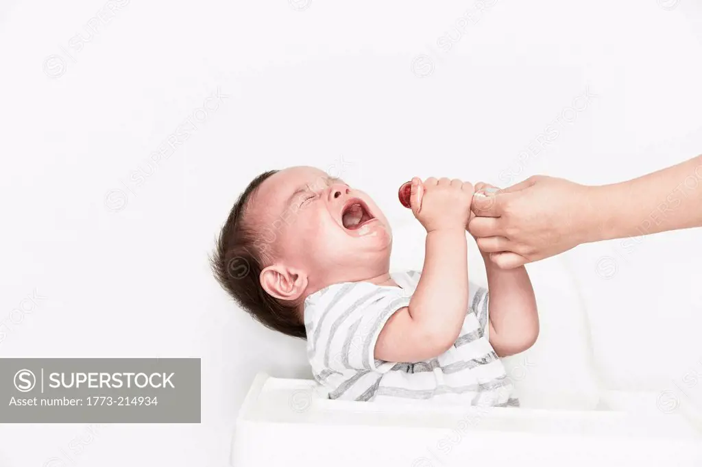 Hand taking lollipop from crying baby