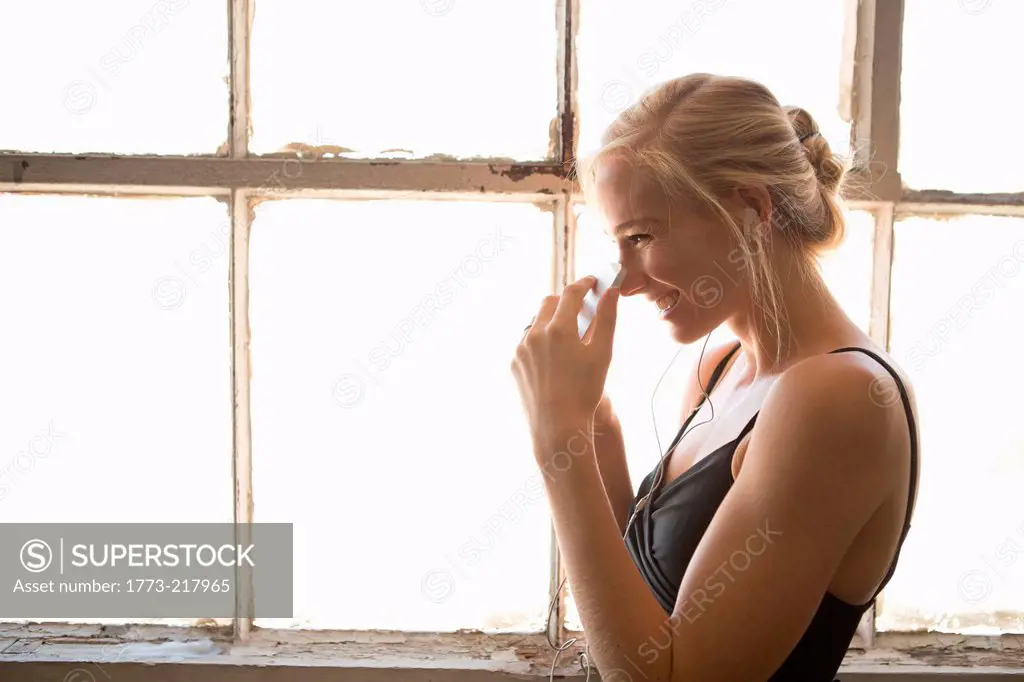 Ballet dancer holding cell phone by window, laughing