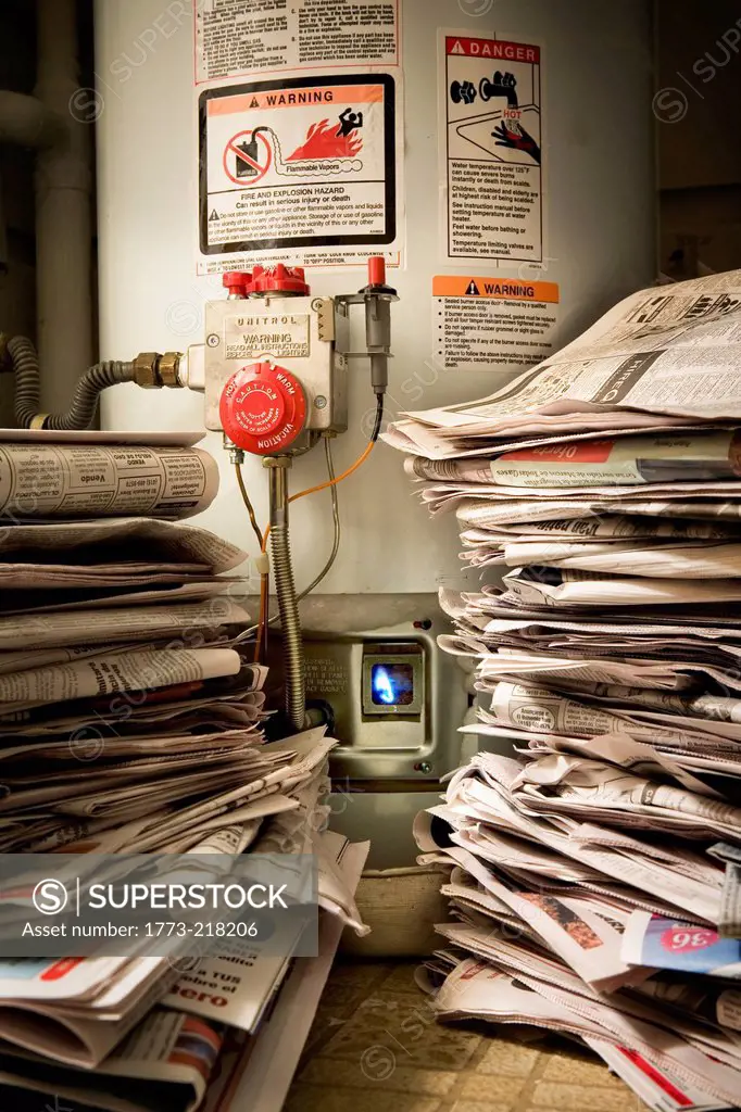 Piles of newspapers next to lit gas boiler