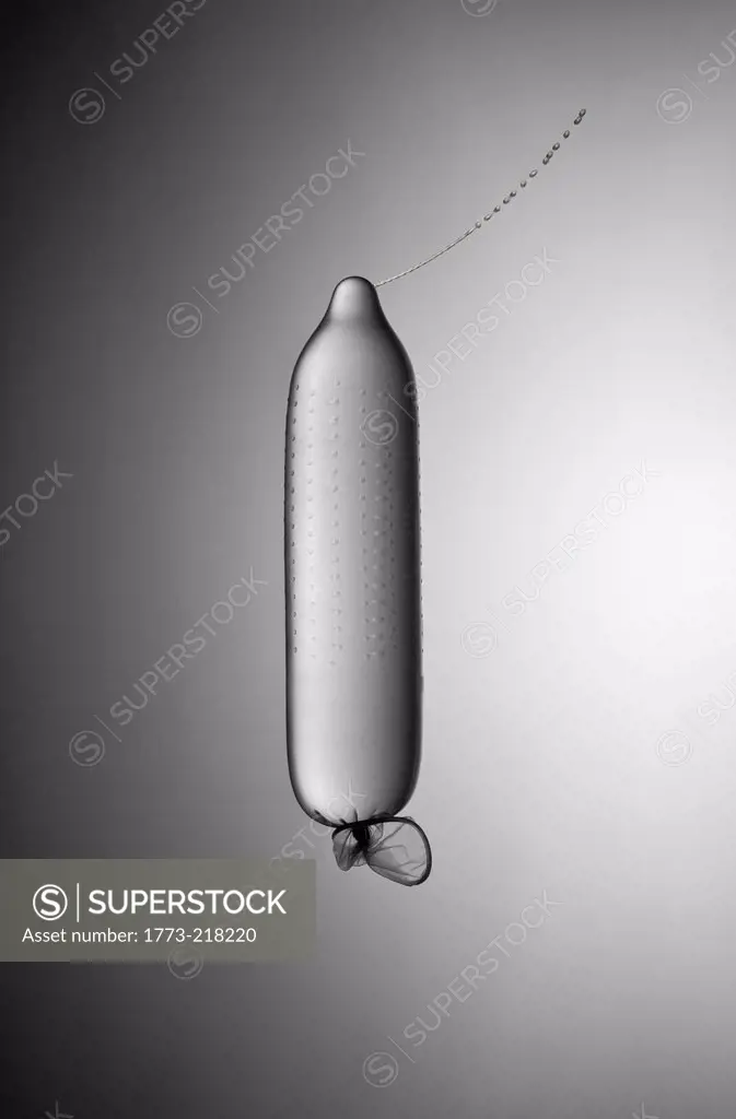 Still life of condom leaking squirt of water