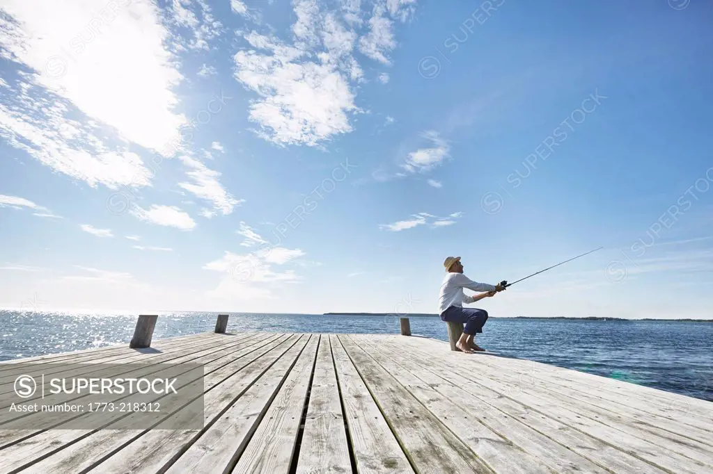 Mid adult man fishing off pier, Utvalnas, Sweden