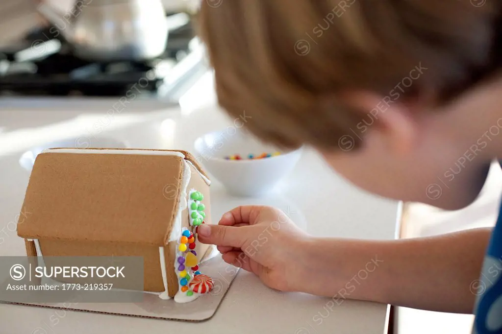 Boy decorating gingerbread house