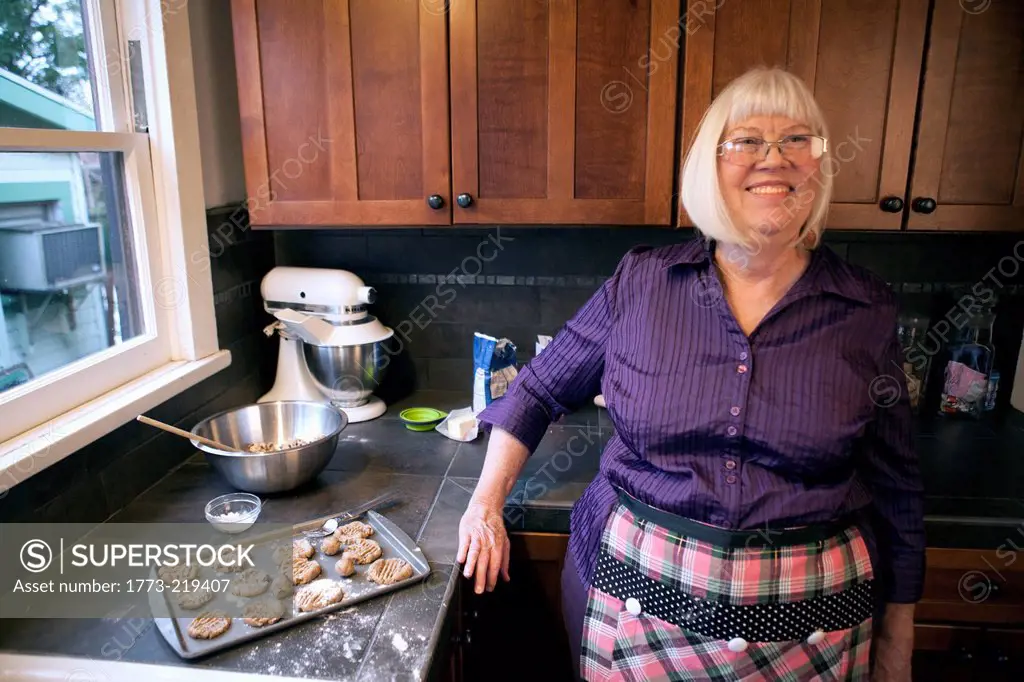 Senior woman standing in kitchen with tray of homemade cookies