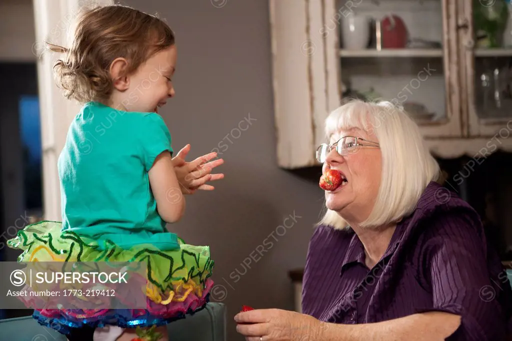 Girl feeding grandmother a strawberry