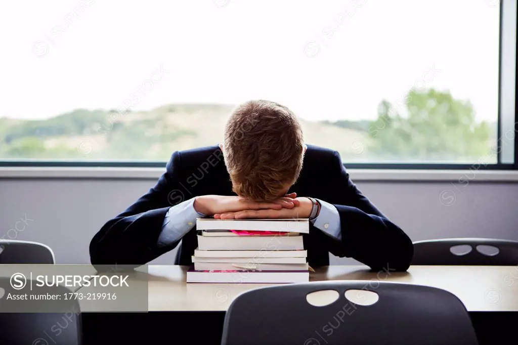 Teenage schoolboy sitting at desk with head down