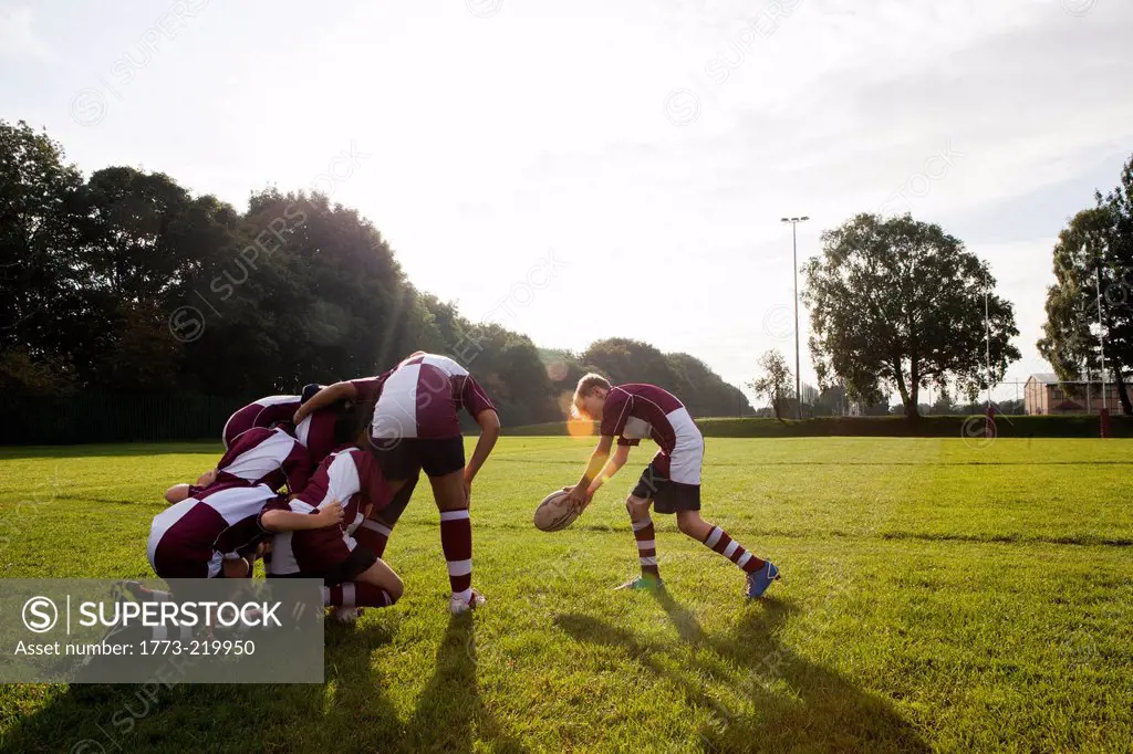 Teenage schoolboy rugby team taking ball from huddle